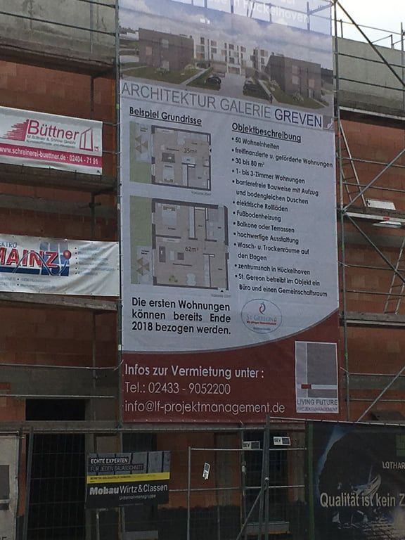 Gerüstlagen und Bauschilder vor der Ziegelfassade eines Wohnungsneubaus